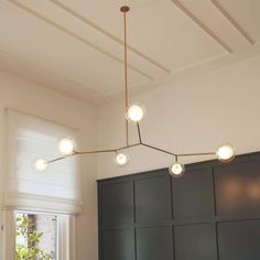 a kitchen with black cabinets and lights hanging from the ceiling