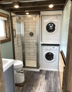 a washer and dryer in a small bathroom with wood flooring on the walls