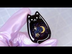 a black cat with stars and moon on it's back sitting on a pink pillow