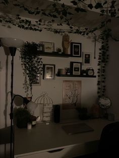 a desk with some plants and pictures on the wall above it in a dark room