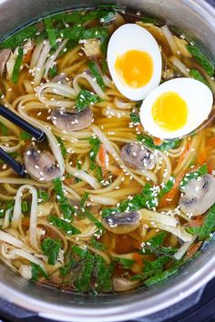 two eggs are sitting on top of noodles in a pot with broccoli and carrots