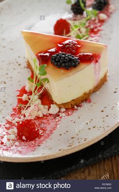 a piece of cheesecake with berries and whipped cream on a white plate stock photo