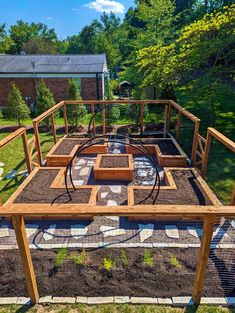 an outdoor garden area with raised beds and plants in the center, surrounded by brick pavers