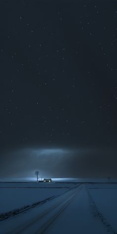 a truck driving down a snow covered road under a night sky with stars above it