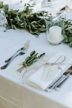 place setting with napkins, silverware and greenery