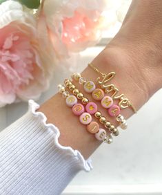 a woman's arm with five bracelets on it and flowers in the background