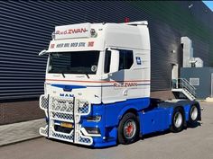 a white and blue semi truck parked in front of a building