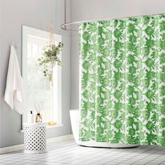 a bathroom with a green shower curtain and white tile flooring in front of a window