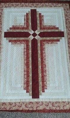 a quilted wall hanging with a red cross on it's center and two sides