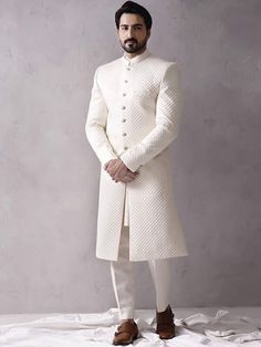 Item Contains:  Sherwani kurta and Pants   Color :  white Fabric :  Quilted silk fabric Style and Designs :  sherwani has mandarin collar and long sleeves with a full button placket even hem and multiple straight slits Kurta has mandarin collar and long sleeves with symmetric hem and multiple slits Pants boot cut style pants with 2 pockets and a fly on zip and hooks  Size :  Slim fit  Model height is 6 fit and wearing 40 size  Material and Care :  Polyester mix  Only dry clean  Note :  There mig White Bandhgala For Formal Winter Events, White Dabka Sherwani For Groom, Fitted White Sherwani For Groom, White Fitted Sherwani For Groom, White Fitted Bandhgala For Groom, White Sherwani For Groom For Eid, White Fitted Kurta For Groom, Festive White Sherwani For Winter, White Fitted Sherwani For Winter