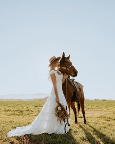 a bride and groom standing next to a horse in the middle of an open field