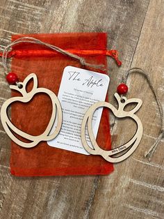 two wooden apple shaped bookends sitting on top of a red cloth covered bag