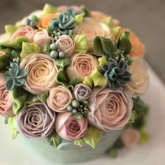 a bouquet of flowers sitting on top of a white cake covered in fondant and succulents