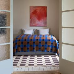 a bed sitting under a painting on top of a wooden floor next to a doorway