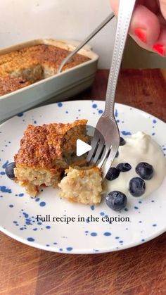 a person is cutting into a piece of cake on a plate with blueberries and yogurt