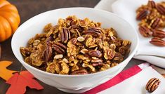 a white bowl filled with granola next to some pumpkins and other autumn decorations