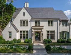 a large white house with lots of windows and steps leading to the front door is shown