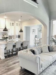 a living room filled with furniture next to a kitchen and breakfast nook area on top of a hard wood floor