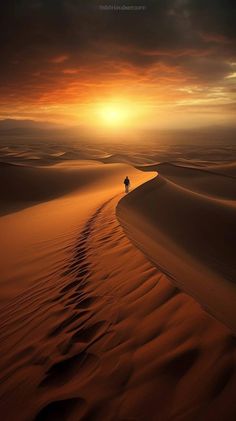 a lone person walking through the desert at sunset