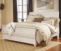 a white bed sitting in a bedroom on top of a hard wood floor next to a window