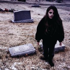 a woman walking in front of two headstones