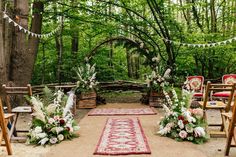 an outdoor ceremony setup with floral arrangements and greenery on the ground, surrounded by wooden chairs