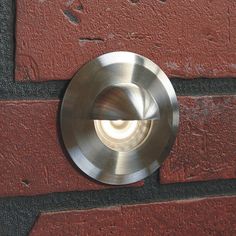 a close up of a metal object on a brick wall with a light in the middle