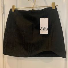 A Unique And Stylish Black Mini Skirt From Zara. Featuring A Geometric Pattern (Looks Like Wood Grain?) And A Unique Cut-Up Hem Detail On One Side In The Front, This Skirt Is One-Of-A-Kind. The Skirt Is Made From High-Quality Polyester Material And Has A Zip Closure For Easy Wear. This Skirt Is A Size Medium And Has A Short Length, Making It Perfect For A Night Out Or A Casual Day. The Skirt Is A Regular Size Type And Not Stretchy. It Is Ideal For Any Woman Looking To Add A Touch Of Sophisticati Zara Stretch Mini Skirt, Zara Mini Skort For Party, Zara Mini Skort For Night Out, Zara Mini Skirt For Night Out, Zara Fitted Mini Skort, Zara Fitted Mini Skirt With Lining, Zara Black Skort For Party, Zara Black Mini Length Skort, Zara Fitted Mini Skirt