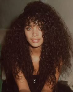 a woman with long curly hair sitting on a couch