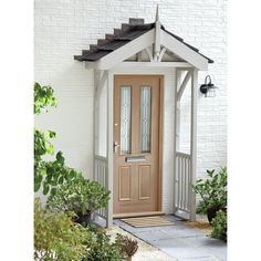 a white brick house with a wooden front door and sidelights on either side of it