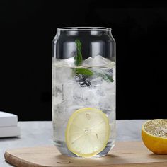 a glass filled with ice and lemon sitting on top of a cutting board