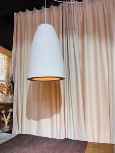 a white lamp hanging over a bed next to a window with curtains on the side