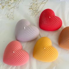 four heart shaped cushions sitting on top of a white sheet