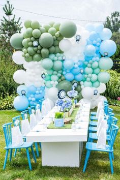 a table with blue chairs and balloons on it in the middle of a lawn area