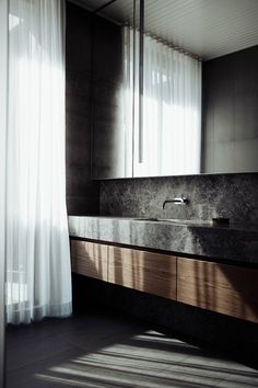 a bathroom sink sitting under a window next to a curtain