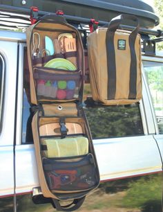 the back end of a car with luggage hanging from it's roof rack and two suitcases on top