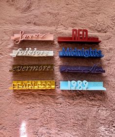 four different colored metal name tags on a pink carpeted surface with the words red, white, blue, and yellow