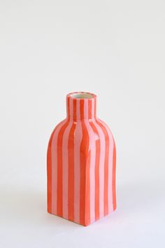 an orange and white striped vase on a white background