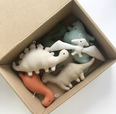 four dinosaur ornaments in a box on a table