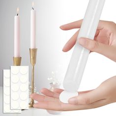 a person holding a white candle in their hand next to a set of three candles