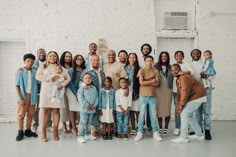 a large group of people standing next to each other in front of a white brick wall