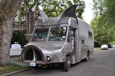 an old silver truck with a shark fin on it's hood parked in front of a tree