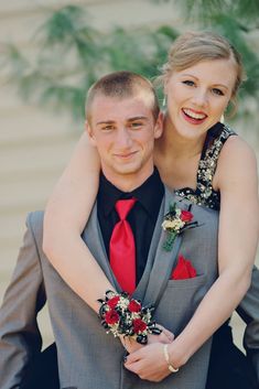 a man in a suit holding a woman on his back and smiling at the camera