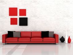 a red couch sitting in front of a white wall with black and grey squares on it