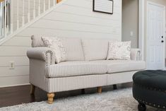 a living room filled with furniture next to a stair case and white walls in the background