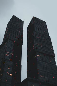 two very tall buildings with lights on them