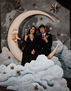 a man and woman sitting on top of a cloud next to a painting of the moon