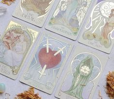 four tarot cards with angels on them sitting next to some stones and shells in front of them