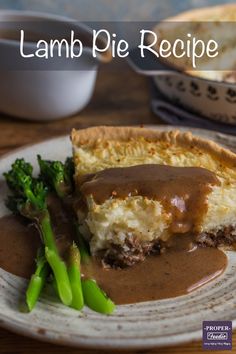 a piece of meat pie with gravy and asparagus on a plate