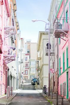 an alley way with pink buildings and green shutters on both sides in the city